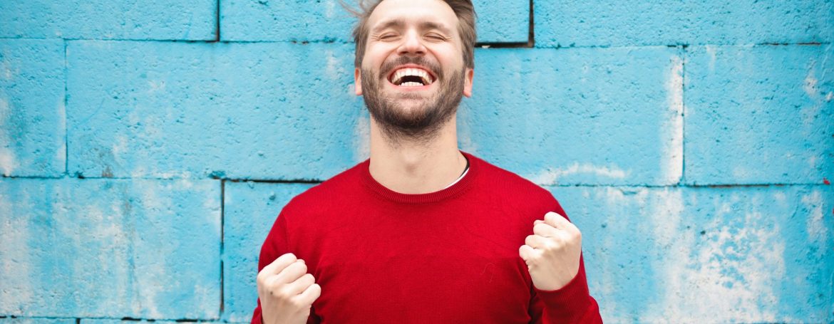 man wearing red long-sleeved shirt standing beside wall