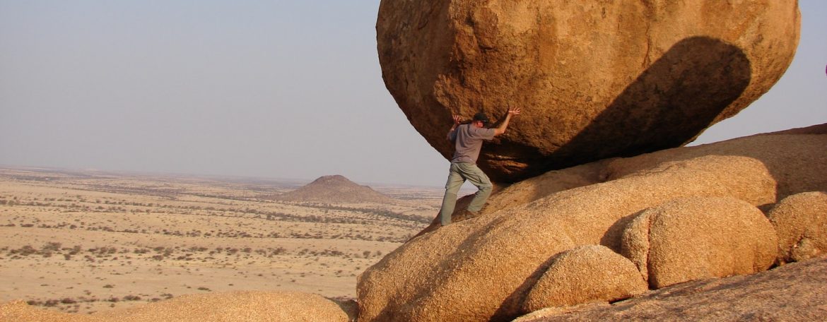 man standing beside rock formation