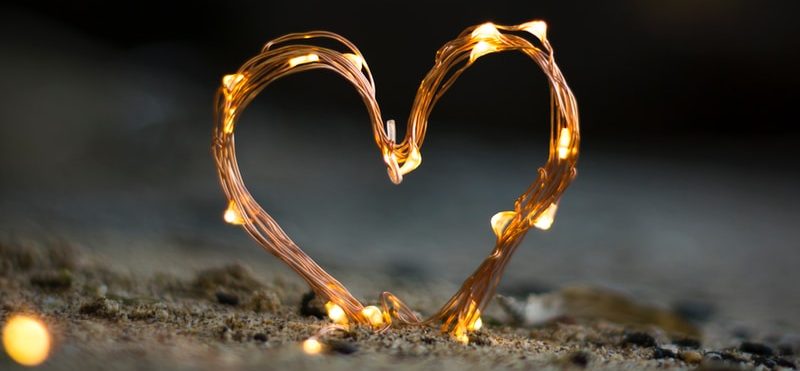 close-up photography of heart shaped fairy lite on brown sand
