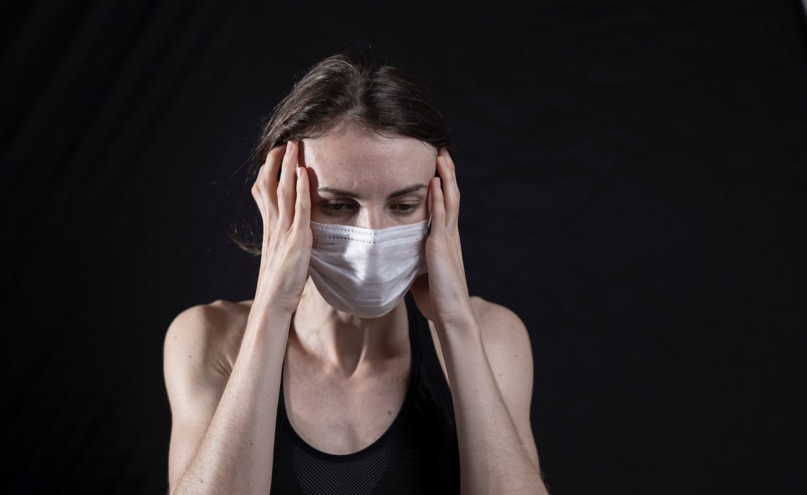 woman in black tank top covering her face with her hands