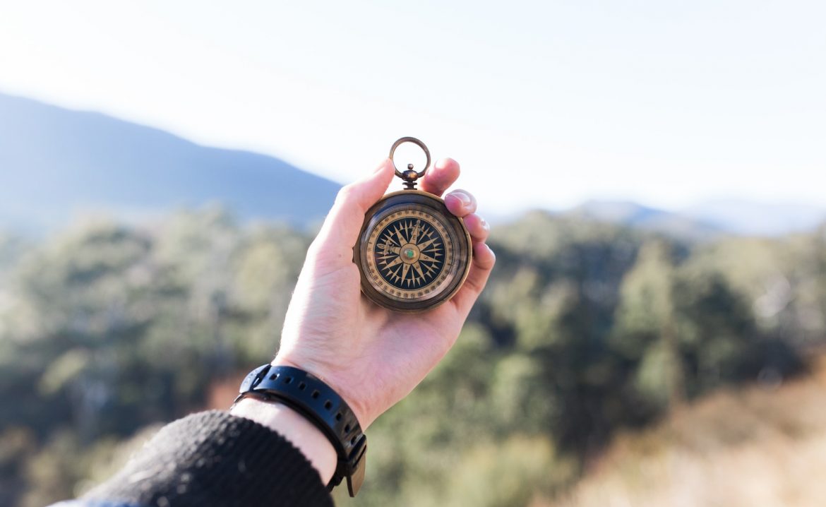 person holding compass selective focus photography