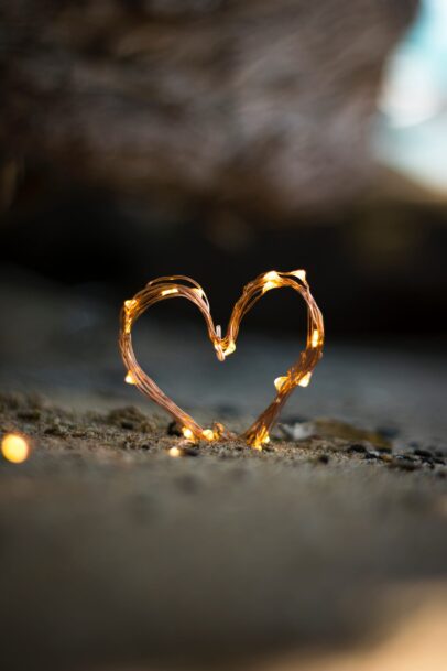 Photo by Fadi Xd close-up photography of heart shaped fairy lite on brown sand